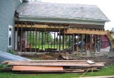 At the end of the ell and across the gable, wide LVLs are fastened to the outside face of the studs to pick up roof and floor loads when the walls are removed.