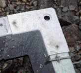 At footing corners, short rebar pins driven into the ground hold corner forms in place. A knockout hole in the bottom of the corner receives the pin.