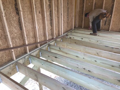 The crew snaps layout lines across the joists for every third row.