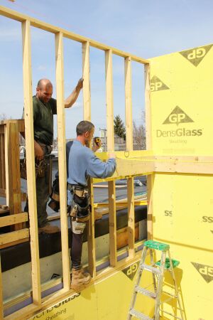 Framers attach a ledger for a stair landing to the stairwell shaft wall, after first fastening a strip of GP Gold Bond gypsum board in place at the ledger location. Framing multiple fire-protected elevator and stairwell shafts is tricky when no wood-to-wood contact between the shafts is allowed, observed contractor Rob Paisley. This staircase will help keep the shaft plumb and stable as the walls rise.