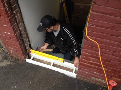 To raise the threshold above grade, a concrete curb was formed and poured on top of the concrete steps into the basement. The PVC form is leveled in the opening and will stay in place after the concrete cures.