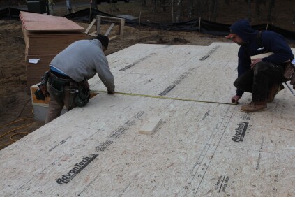 The crew measures up from the secondary baseline for the end of the one of the front walls of the house.