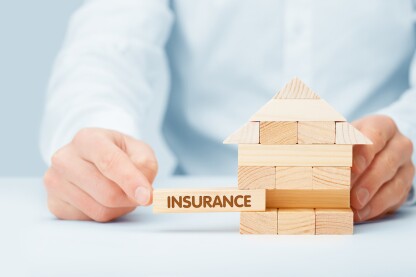 Property (family house) insurance protection concept. Insurance agent complete wooden model of the house with last piece with text insurance.