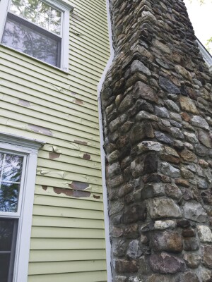 Honey bees were entering the wall cavity through a large cap along the stone chimney.