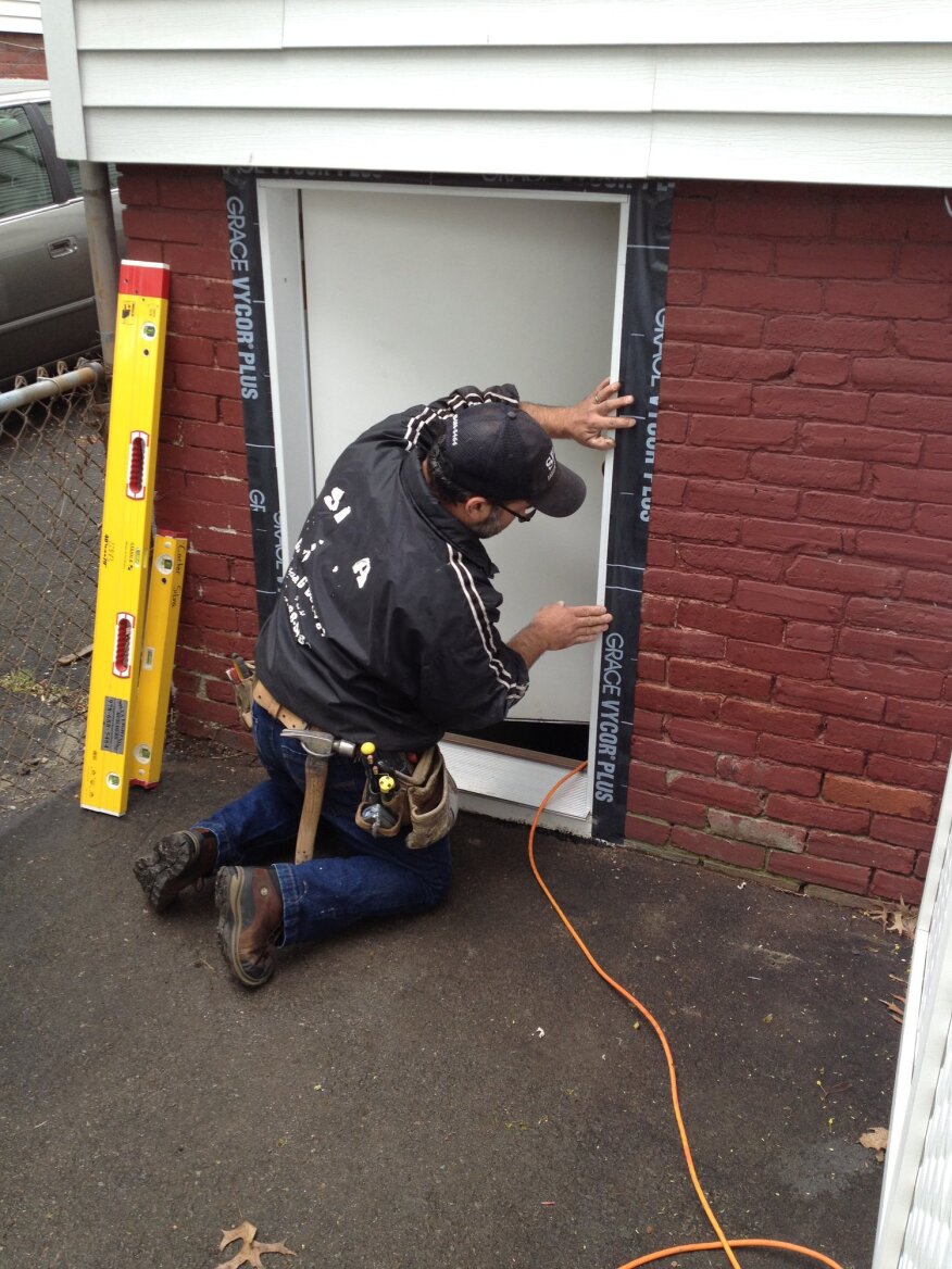 Self-adhered flashing tape weather-seals the gap between the door jamb and the brick.