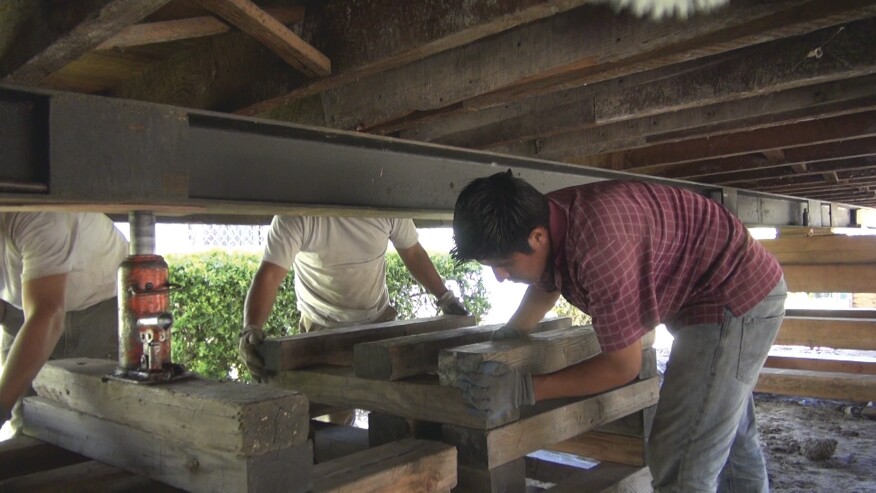 When the building is raised and oriented over its footing, he suspends the house on cribbing to allow reconstruction of the foundation and cripple wall.
