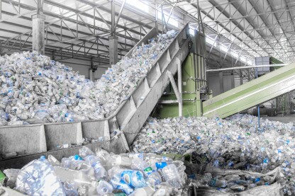 An escalator with a pile of plastic bottles at a factory for processing and recycling PET plastic.