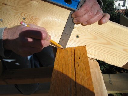 To find the long points for the lower plate of the dropped gable, set a square to 5 inches (3 1/2 inches for the lookouts and 1 1/2 inches for the top plate). Slide the square down the rafter and mark where it touches the top of the wall.