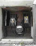 The author's company was hired to replace this original 1920s electrical service; it posed a hazard because it was old, undersized, not grounded, and in an outdoor ground-level wooden enclosure next to the driveway.