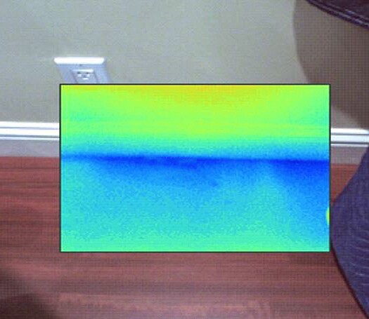 An infrared image shows air getting pulled from under the baseboard during a blower-door depressurization test.