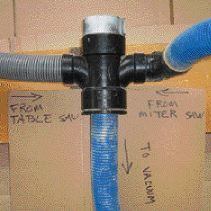 A homemade air valve is made from standard plumbing and electrical fittings. Rotating a piece of plastic conduit directs suction to a particular saw.