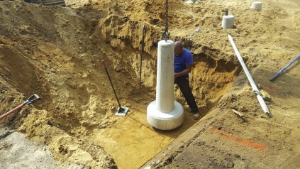 The site crew dug the hole for each precast footing individually, compacting the base of the hole and using a laser level to set the elevation.