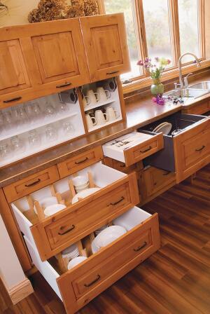 Designer Sarah Michalowski placed dish and utensil storage to the left of the sink and drawer dishwasher. “Itís all in one area. [The homeowner] can put away dishes or set them on the island behind him for a meal,” she says. The adjustable peg dividers in the drawers are part of the semi-custom cabinetry line. “It saves us from having to order that and having the installer cut it to size and put it in,” she says.