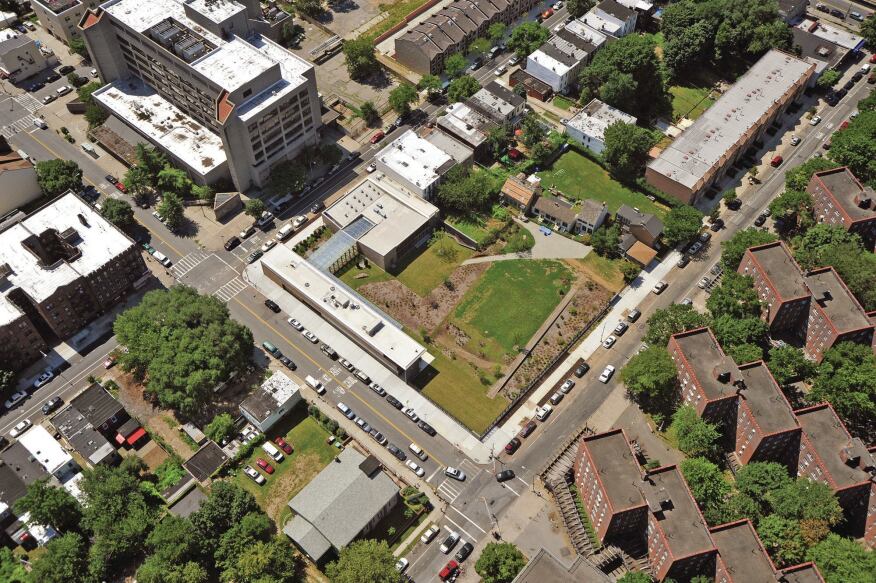 An aerial view shows how the new center frames the four historic houses (at upper right) on the 1.5-acre site. Where not bounded by buildings, the perimeter is enclosed by a cast-iron fence from Allen Architectural Metals.