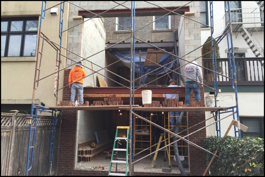 The two-story block addition was “shoe-horned” in between abutting one- and two-story additions to the right and left. Masons apply brick veneer to the two-story block addition’s rear façade.