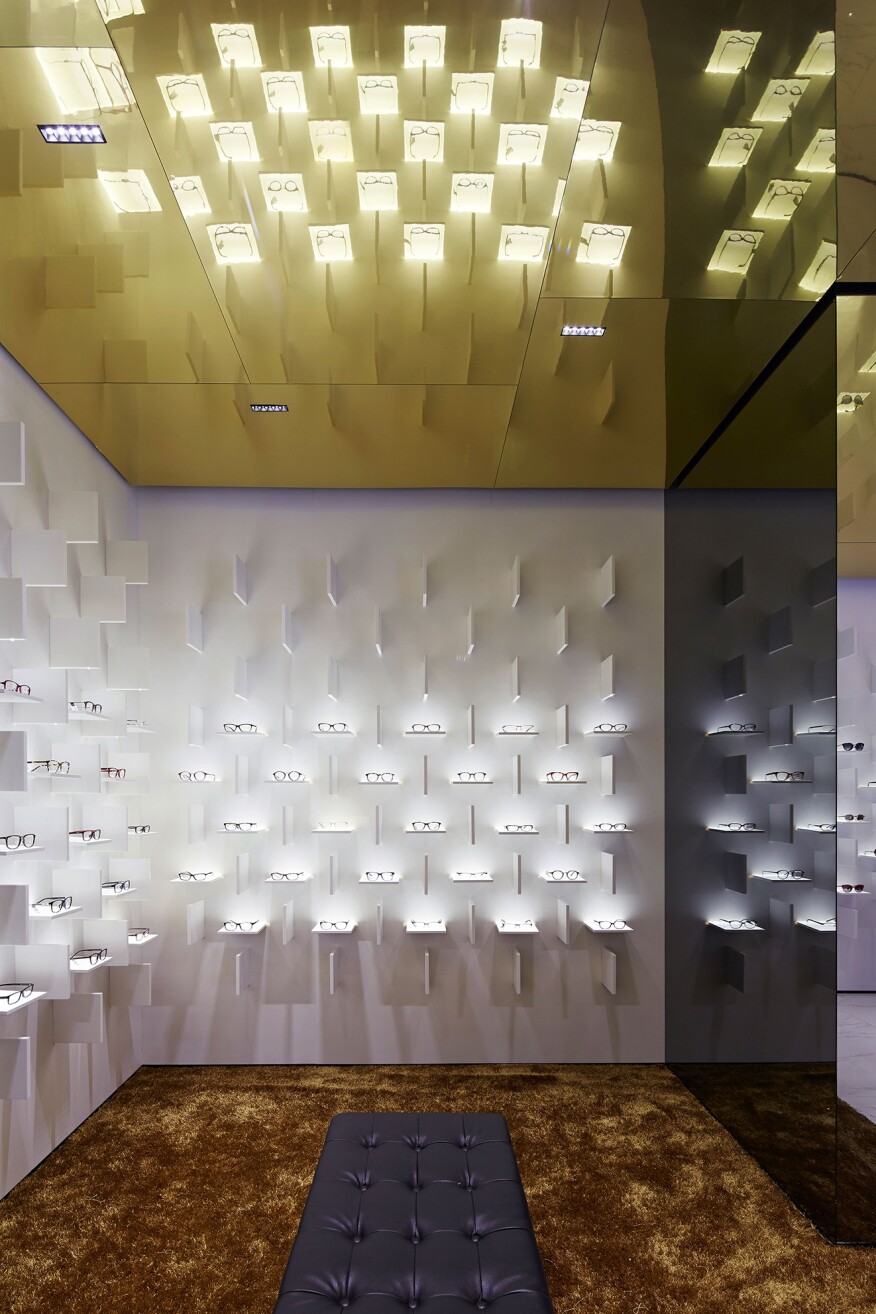 The gold-toned ceiling and the gold-hued carpet provide a contrast to the white backdrop of the main eyewear displays.