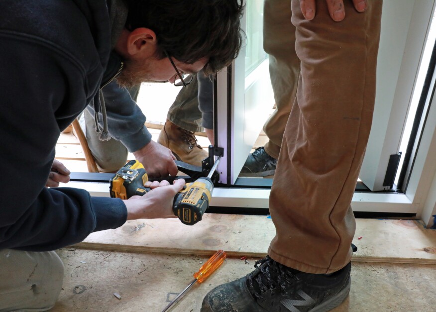 The bottom hinge is secured to the door and guide at the bottom of the panel. A door jack helps set the door at the right elevation.
