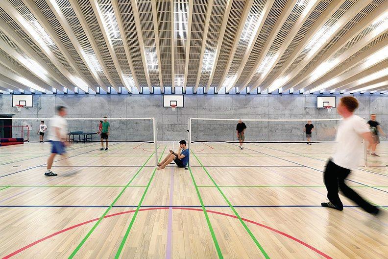 Linear fluorescent fixtures are mounted between the glulam beams and provide a contrast in color temperature with the daylight at the clerestory perimeter.