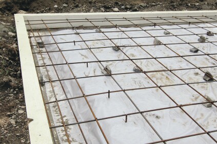 Each intersection is wire-tied together and anchored to the vertical rebar sections. An additional layer of rebar below the main layer reinforces the built-up edge of the slab.