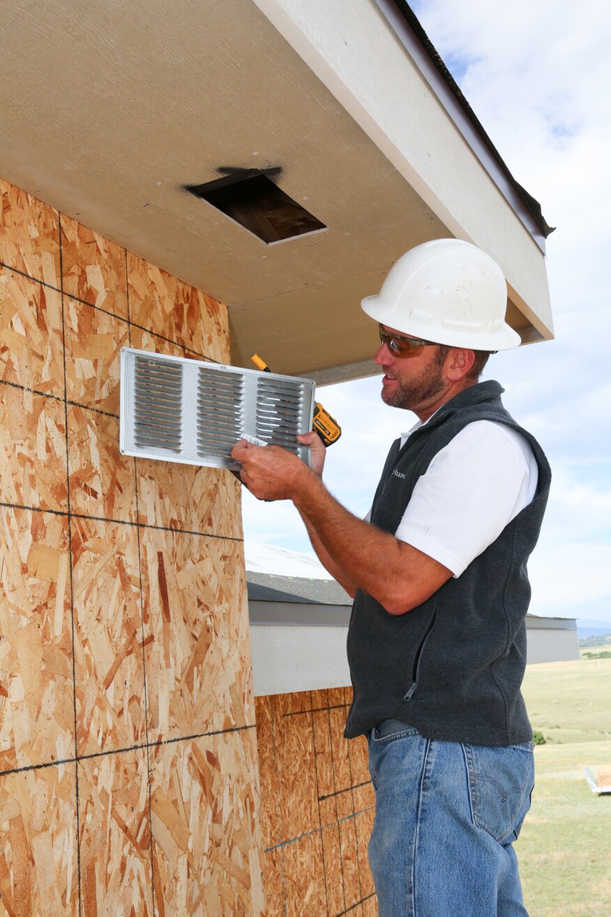 Colorado Springs builder Andy Stauffer installs a screened vent in the soffit of a home near the city.