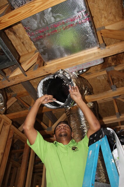 He butters the inner liner of the flex duct with mastic.