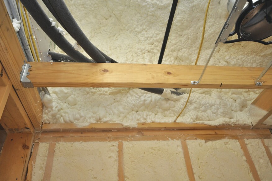 The rim-joist area and the wall above the rim joist are insulated to the roofline of the attached garage with 6 inches of closed-cell foam. This not only insulates the wall but also seals all penetrations.